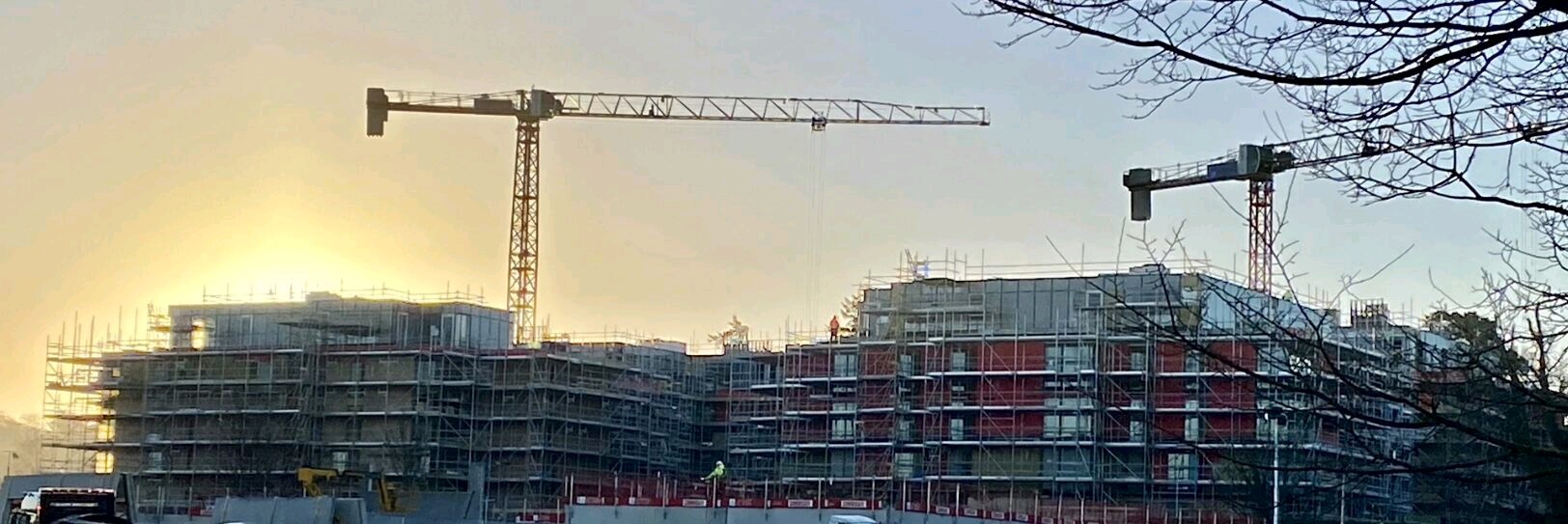 Sunrise over apartment construction with two tower cranes